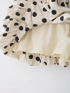 Vue détaillée de la jupe beige à pois montrant les bords volantés et la texture du tissu