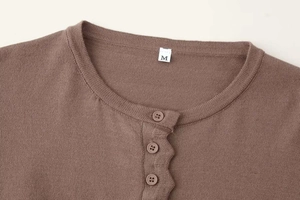 Close-up of brown knit cardigan featuring round buttons and a visible size M label