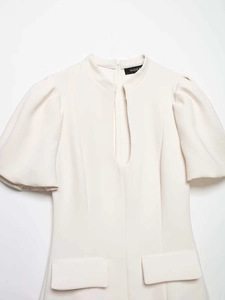 Vue détaillée robe beige avec manches bouffantes, découpe verticale et poches décoratives