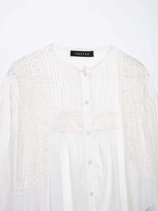 Detail eines weißen Baumwollhemdes mit Markenlabel und feinen Spitzenapplikationen