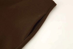 Detail view of dark brown wool-blend trousers showing invisible pocket seam and texture