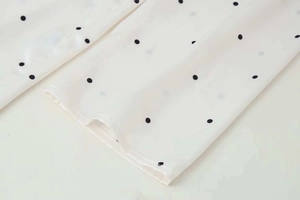 Close-up of the stitching and lightweight polka dot chiffon fabric on a white blouse