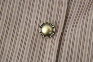 Gros plan sur un bouton en laiton et tissu marron à rayures de veste de travail