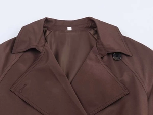 Detail of classic wide lapel and texture on brown trench coat with black button