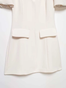 Détail de la robe crème à manches bouffantes avec poches à rabat et tissu texturé