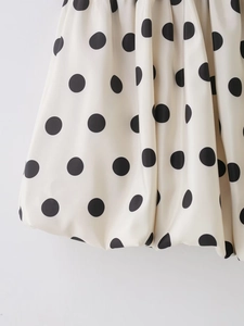 Détail du tissu à pois crème avec ourlet ballon structuré et texture satinée élégante
