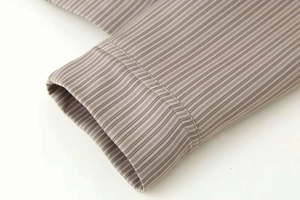 Vue détaillée de la texture du tissu rayé et des coutures sur les poignets de la chemise
