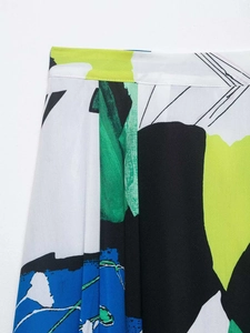 Detail shot of pleated midi skirt featuring abstract green and blue artistic prints