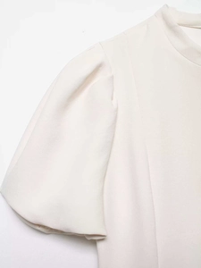 Détail d'une robe crème à manches bouffantes avec épaules plissées et texture en crêpe