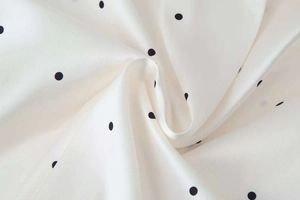 Detailed view of polka dot satin fabric with a silky glossy finish and elegant drapes