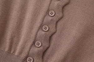 Detail of brown knit cardigan featuring scallop edge trim and matching small buttons