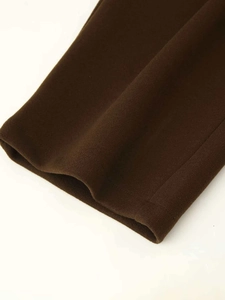 Detailed close-up of dark brown wool blend fabric with clean stitching on pants hem