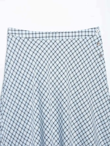 Détail d'une jupe à carreaux bleu clair et noir avec des boutons ronds décoratifs