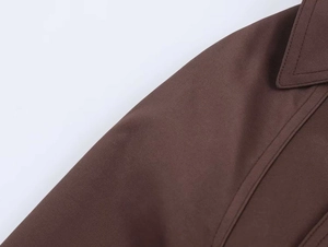 Detailed macro view of dark brown twill fabric texture and stitching on trench coat