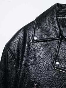 Detailed macro shot of black lychee grain leather biker jacket with silver rivets