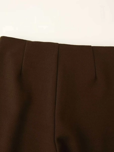 Macro view of dark brown high-waisted trousers showing precise darts and brushed texture