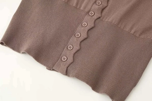 Detailed close-up of brown knit cardigan featuring wavy edges and premium buttons