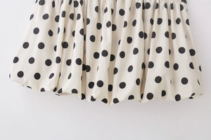 Gros plan sur l'ourlet bulle d'une jupe blanche à motif classique de pois noirs