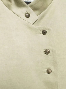 Detail of light olive shirt showing bronze floral buttons and textured fabric