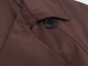 Detail view showing a dark brown trench coat collar with precise stitching and a round button
