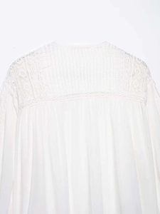 Detailansicht der weißen Baumwollbluse mit Spitze und plissierten Stoffstrukturen