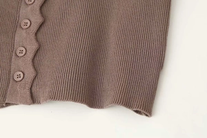Close-up of brown knit cardigan with scalloped edges and matching resin buttons