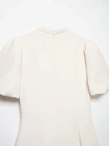 Détail des manches bouffantes et zip invisible au dos de cette robe beige sobre