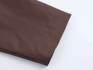 Detailed macro shot of dark brown twill fabric texture on a stylish autumn trench coat