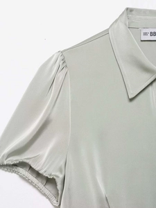 Close-up of lapel collar and puff sleeve detail on a satin short-sleeved blouse