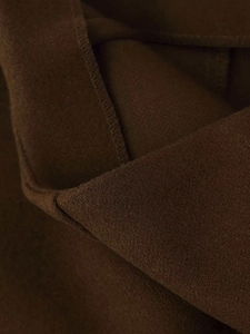 Macro shot of dark brown fabric texture and detailed stitching on cropped trousers