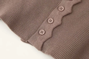Detail of a dark purple ribbed knit cardigan showing textured fabric and three matching buttons