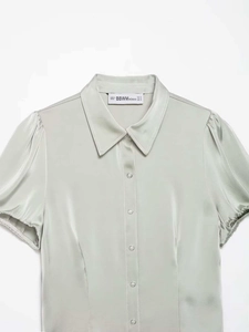 Detailed view of light green satin shirt featuring classic lapel and puff sleeves