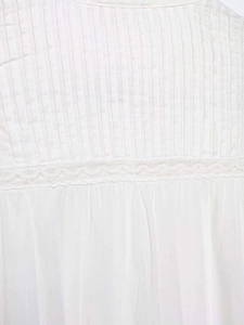Detail der weißen Baumwollbluse mit feinen Plisseefalten und Spitzenbesatz