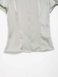 Detailed view of women's short sleeve satin shirt with silver buttons and princess seams