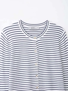 Dettaglio del cardigan a righe blu e bianche con bottoni dorati ed etichetta