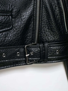 Close-up of litchi-textured black leather jacket belt with silver buckle and metal eyelets