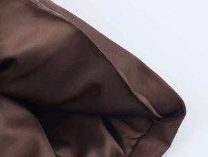 Close-up of deep brown trench coat fabric showing detailed twill weave and smooth inner lining