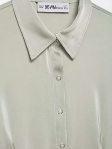 Macro view of silky light green satin shirt collar with metal snaps and size label