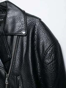 Detail of black lychee grain faux leather biker jacket with silver zippers and metallic snaps