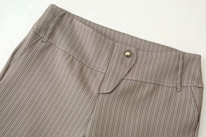 Gros plan du pantalon marron à fines rayures avec taille large et bouton en métal