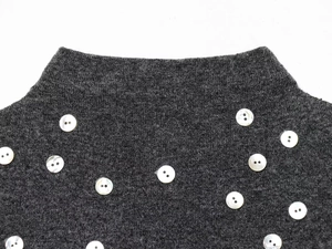 Dettaglio del top in maglia grigio scuro con collo alto e bottoni decorativi bianchi