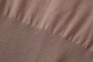 Macro shot of taupe knit fabric texture with ribbed hem detail and fine stitch density