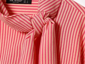 Detail of the pink striped poplin shirt featuring a large bow-tie collar and brand label