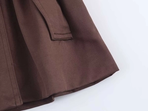 Detail shot of brown trench coat side pocket with precise stitching on twill fabric