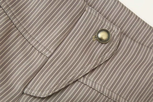 Détail de veste utilitaire à rayures grises avec poche à rabat et bouton en métal vintage