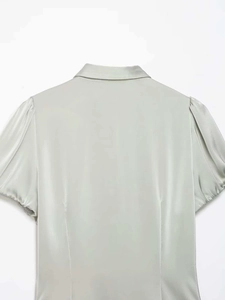 Close-up of smooth satin fabric and puff sleeve detail on light green short sleeve shirt