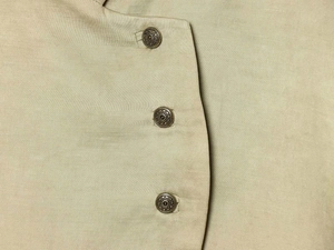 Detail shot of vintage bronze sunflower buttons on light khaki blazer jacket fabric