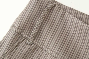 Détail de la texture du tissu tissé à rayures et des passants de ceinture du pantalon