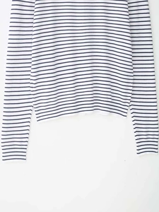 Dettaglio della trama a maglia a righe blu navy su orlo e polsini di un maglione bianco
