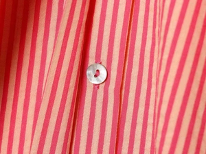 Close-up of striped poplin shirt fabric with a polished mother-of-pearl button detail